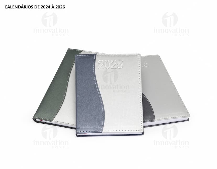 Agenda Diária 2025 aberta sobre uma mesa de escritório, ao lado de um notebook, papéis em branco, envelope, livro, mensagens, páginas vazias, pastas de escritório, documentos e um bloco de notas. A imagem representa um ambiente corporativo e de organização.