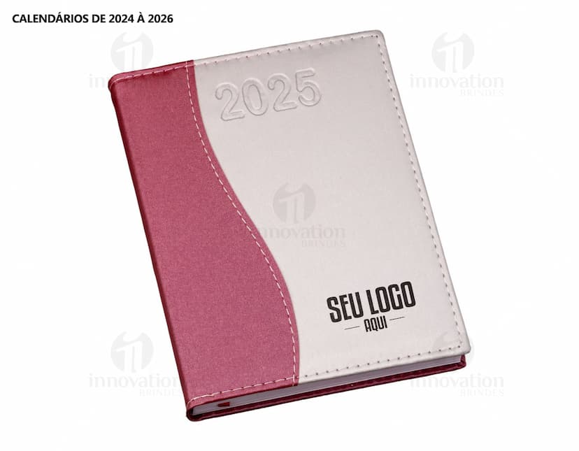 Agenda Diária 2025 aberta sobre uma mesa de escritório, ao lado de um notebook, papéis em branco, envelope, livro, mensagens, páginas vazias, pastas de escritório, documentos e um bloco de notas. A imagem representa um ambiente corporativo e de organização.