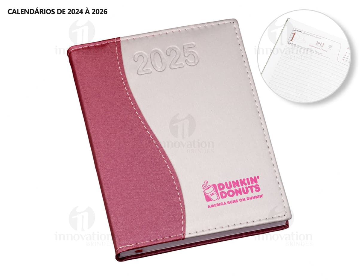 Agenda Diária 2025 aberta sobre uma mesa de escritório, ao lado de um notebook, papéis em branco, envelope, livro, mensagens, páginas vazias, pastas de escritório, documentos e um bloco de notas. A imagem representa um ambiente corporativo e de organização.