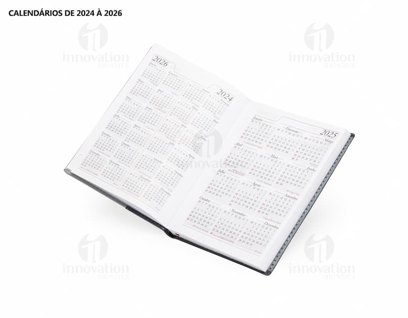 Agenda Diária 2025 aberta sobre uma mesa de escritório, ao lado de um notebook, papéis em branco, envelope, livro, mensagens, páginas vazias, pastas de escritório, documentos e um bloco de notas. A imagem representa um ambiente corporativo e de organização.