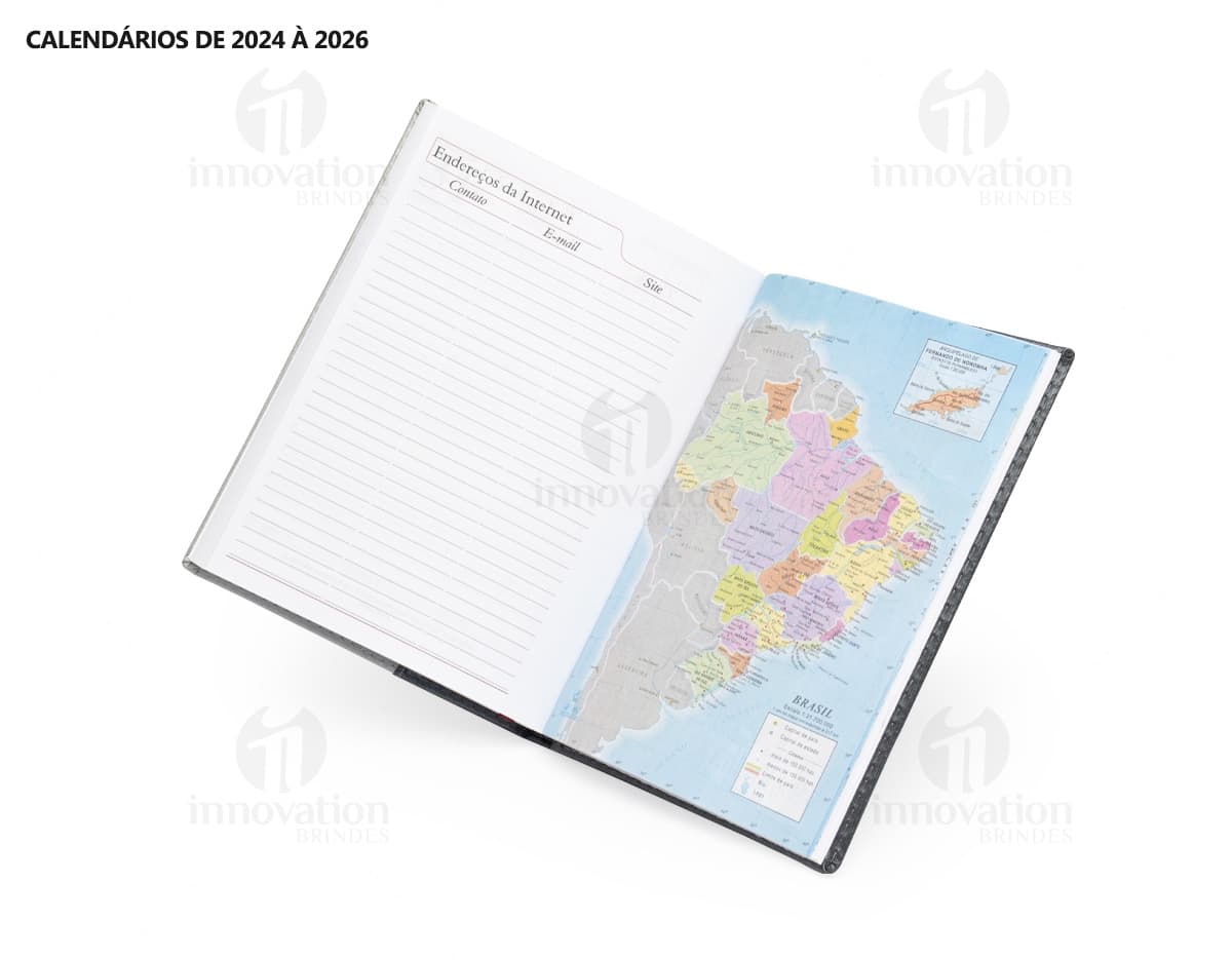Agenda Diária 2025 aberta sobre uma mesa de escritório, ao lado de um notebook, papéis em branco, envelope, livro, mensagens, páginas vazias, pastas de escritório, documentos e um bloco de notas. A imagem representa um ambiente corporativo e de organização.