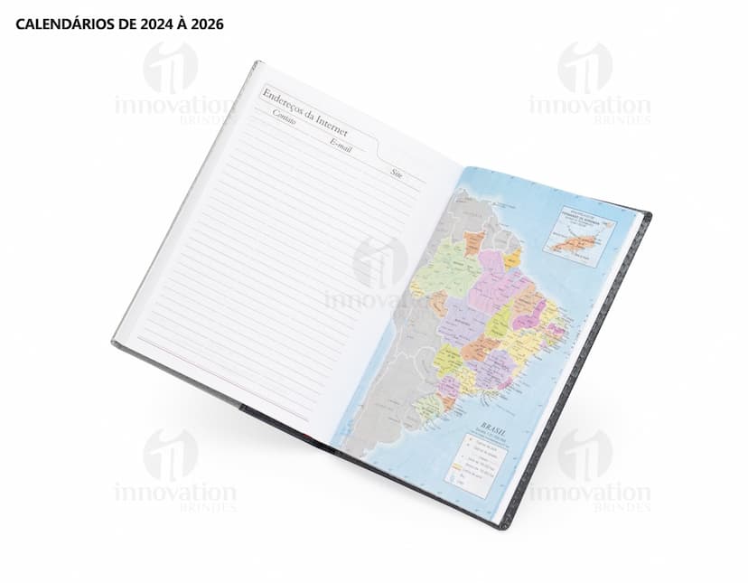 Agenda Diária 2025 aberta sobre uma mesa de escritório, ao lado de um notebook, papéis em branco, envelope, livro, mensagens, páginas vazias, pastas de escritório, documentos e um bloco de notas. A imagem representa um ambiente corporativo e de organização.
