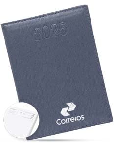 Agenda Diária 2025 de capa preta com detalhes dourados e páginas em branco, sobre uma mesa de madeira com caneta ao lado.