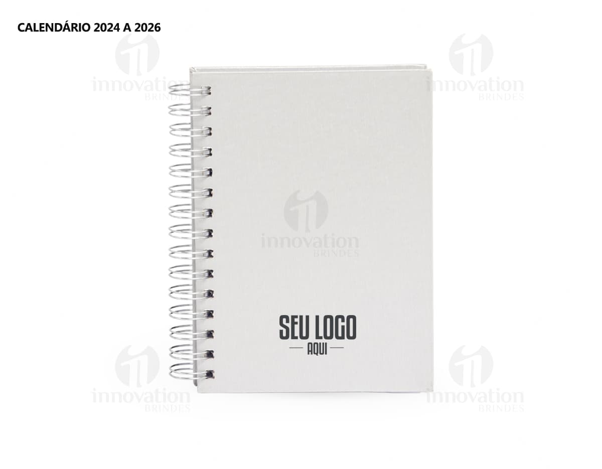 Foto de uma agenda diária para o ano de 2025, com capa marrom e uma espiral para folhear as páginas. Na imagem, é possível ver espaços em branco para escrever notas e lembretes, com um lápis e régua ao lado. A agenda está aberta em uma página em branco, pronta para ser preenchida com informações e compromissos.