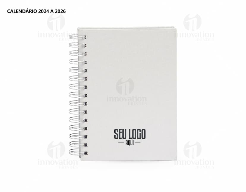 Foto de uma agenda diária para o ano de 2025, com capa marrom e uma espiral para folhear as páginas. Na imagem, é possível ver espaços em branco para escrever notas e lembretes, com um lápis e régua ao lado. A agenda está aberta em uma página em branco, pronta para ser preenchida com informações e compromissos.