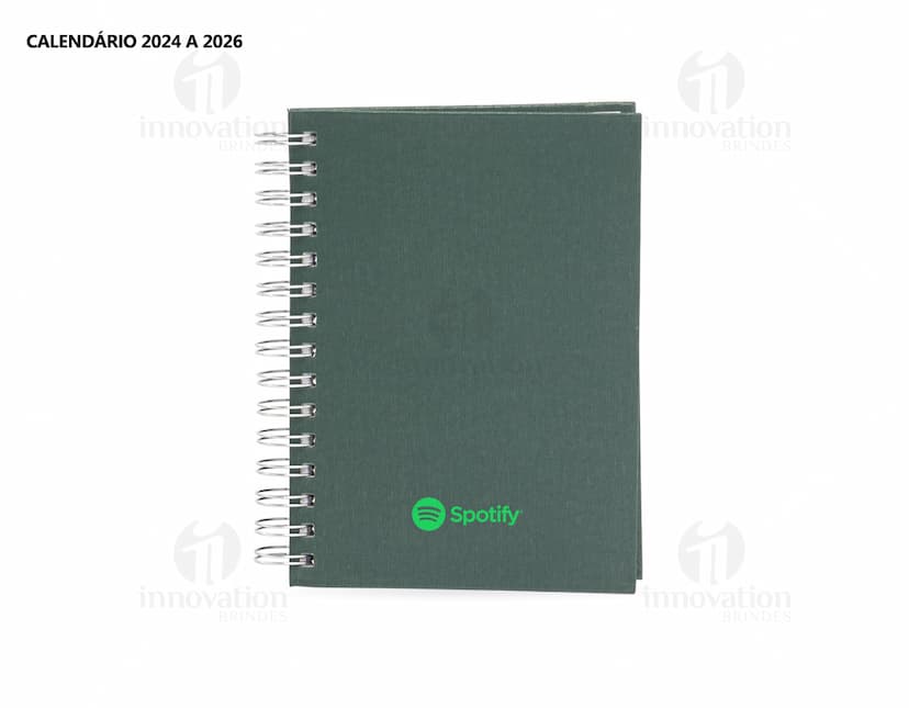 Foto de uma agenda diária para o ano de 2025, com capa marrom e uma espiral para folhear as páginas. Na imagem, é possível ver espaços em branco para escrever notas e lembretes, com um lápis e régua ao lado. A agenda está aberta em uma página em branco, pronta para ser preenchida com informações e compromissos.