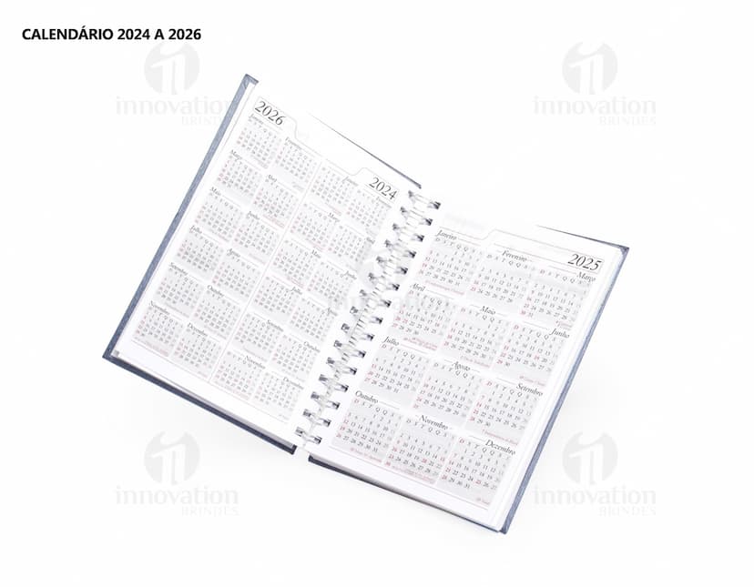 Foto de uma agenda diária para o ano de 2025, com capa marrom e uma espiral para folhear as páginas. Na imagem, é possível ver espaços em branco para escrever notas e lembretes, com um lápis e régua ao lado. A agenda está aberta em uma página em branco, pronta para ser preenchida com informações e compromissos.