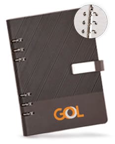 Caderno fichário de couro sintético preto, contendo equipamentos de escritório, papel, computador e documentos. O produto