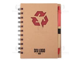 Caderno ecológico com caneta sobre uma mesa de escritório, ao lado de um papel em branco, uma mensagem escrita, um objeto de
