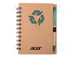 Caderno ecológico com caneta sobre uma mesa de escritório, ao lado de um papel em branco, uma mensagem escrita, um objeto de