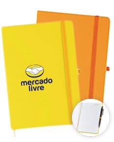 Foto de uma caderneta fosca com pauta, em um design moderno e vazio. O objeto possui um botão de metal e um adesivo laranja na capa. Está aberto, com páginas em branco e espaço para escrever informações.