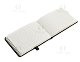 Mini Cuaderno marrón de cuero, abierto, con página en blanco. Al lado, un pen drive, un llavero, un diario negro y un