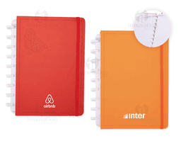 Caderno de Disco em branco com capa listrada amarela e textura de couro aberto em cima de uma pilha de papéis e notas, com um