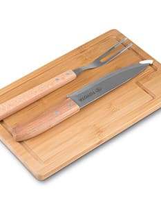 Kit churrasco composto por 3 peças (faca, garfo e espátula) e uma tábua de madeira.
