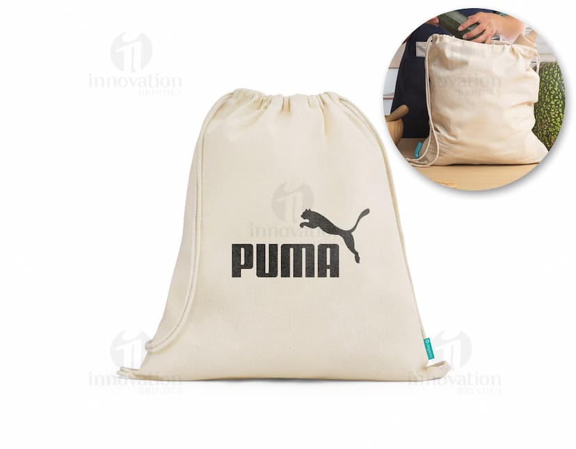 Sacola mochila de algodão orgânico 120 g, vazia e em um tom de amarelo suave. A imagem mostra a sacola aberta, com um design vintage e textura grunge. Ao redor dela, há um envelope, notas de dinheiro, uma página em branco, um livro antigo e um cartão. O cenário remete a uma atmosfera retro e nostálgica, ideal para representar um presente especial.