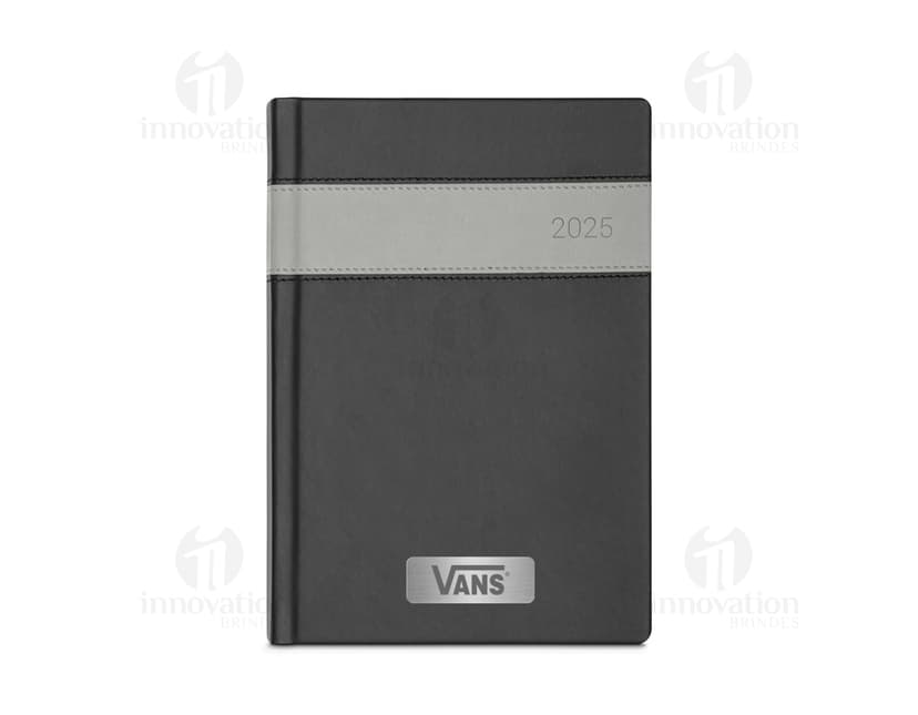 Notebook com capa de couro sintético preto, com marcador de fita colorida. O objeto está aberto, exibindo páginas em branco e tem um disco rígido externo ao lado. Há um bloco de notas, caneta e drive de armazenamento na mesa de escritório.