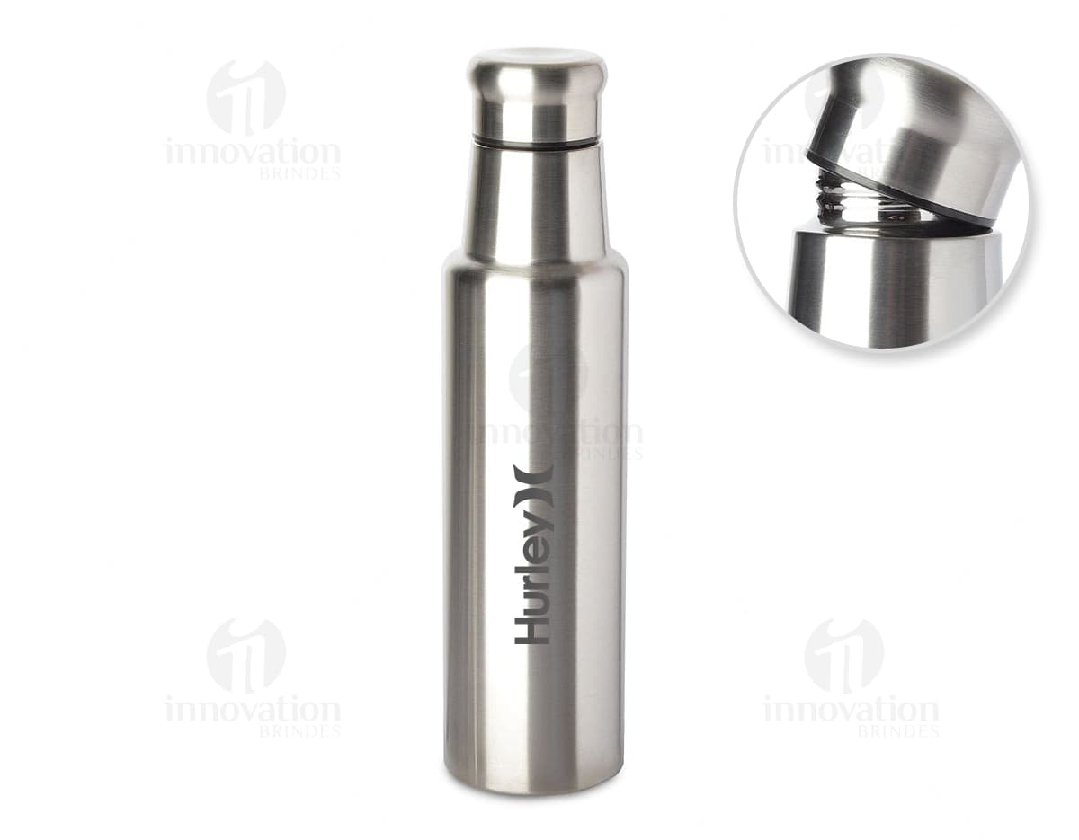 Garrafa de aço inoxidável de 1 litro contendo líquido. O recipiente possui um design limpo e elegante, feito de metal prateado e plástico. Não há ninguém na imagem, apenas a garrafa brilhante refletindo a luz. O produto é moderno e possui tampa, sendo ideal para armazenar bebidas ou produtos de higiene.