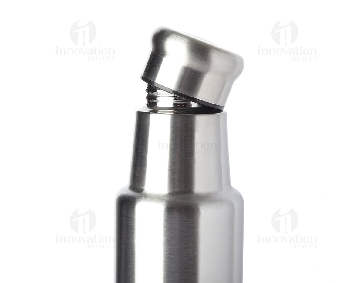Garrafa de aço inoxidável de 1 litro contendo líquido. O recipiente possui um design limpo e elegante, feito de metal prateado e plástico. Não há ninguém na imagem, apenas a garrafa brilhante refletindo a luz. O produto é moderno e possui tampa, sendo ideal para armazenar bebidas ou produtos de higiene.