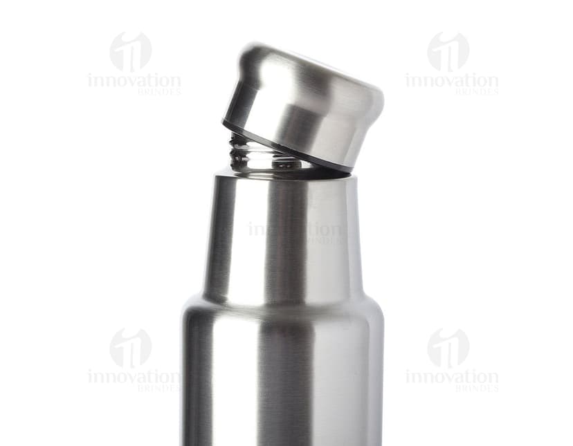 Garrafa de aço inoxidável de 1 litro contendo líquido. O recipiente possui um design limpo e elegante, feito de metal prateado e plástico. Não há ninguém na imagem, apenas a garrafa brilhante refletindo a luz. O produto é moderno e possui tampa, sendo ideal para armazenar bebidas ou produtos de higiene.