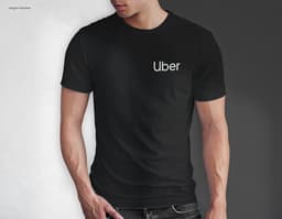 Homem jovem e atraente sorrindo, posando em um estúdio com uma t-shirt preta de algodão tradicional de 165g/m². Ele está a