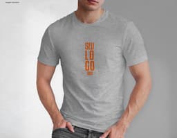 Homem jovem e atraente posando de maneira casual com uma camiseta de algodão tradicional. Ele está sorrindo e tem um sorriso
