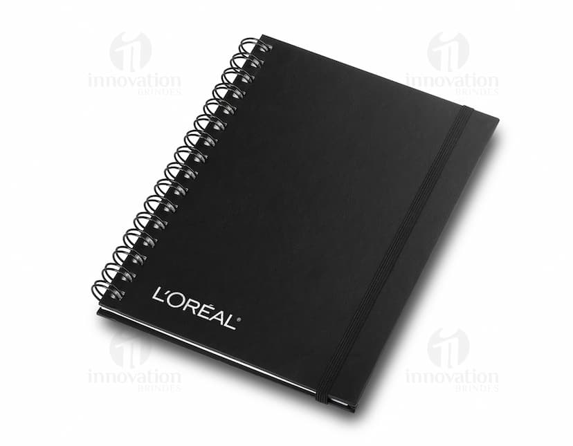 Caderno de negócios aberto com páginas em branco, papel em espiral amarelo e marrom, com espaço para escrever mensagens e lembretes. Pen e lápis ao lado do caderno, sem ninguém na imagem.