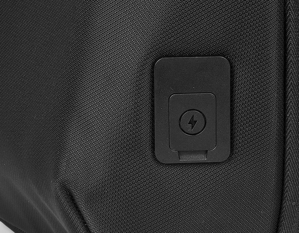Headset preto com fio conectado a um dispositivo moderno, com etiqueta de preço. Aparece também um microfone próximo ao equipamento, indicando uso para escutar música ou comunicação.