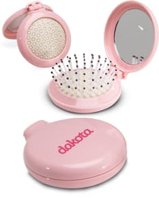 Escova com Espelho em metal prateado, design moderno e redondo, com espelho integrado. Ideal para uso como item de toiletry e maquiagem, com acabamento brilhante e símbolos em tons de preto e dourado.