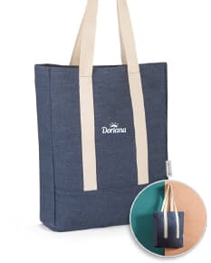 Sacola de denim reciclado com bolso, em tons de marrom e amarelo. Possui alça em couro, fecho com cadeado e etiqueta de preço. Ideal para compras e presente, demonstrando elegância e versatilidade.