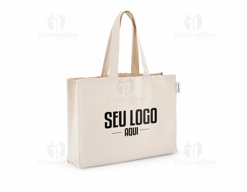 imagem de uma sacola de algodão reciclado 220g/m², com design moderno e elegante, na cor preta e prateada. O objeto está vazio, apresentando um acabamento em couro e um fecho de zíper. A embalagem é transparente e possui alças para transporte. Ideal para compras e como acessório pessoal.