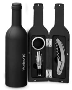 Kit de vinho 3 peças contendo uma garrafa de vinho, copo de vidro e abridor de garrafas em um fundo escuro e elegante. O conjunto é perfeito para celebrações, jantares e eventos especiais.