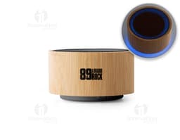 : Caja de sonido de bambú y ABS con Bluetooth versión 5.0 en primer plano, sobre una tabla de cortar. El objeto es metálico