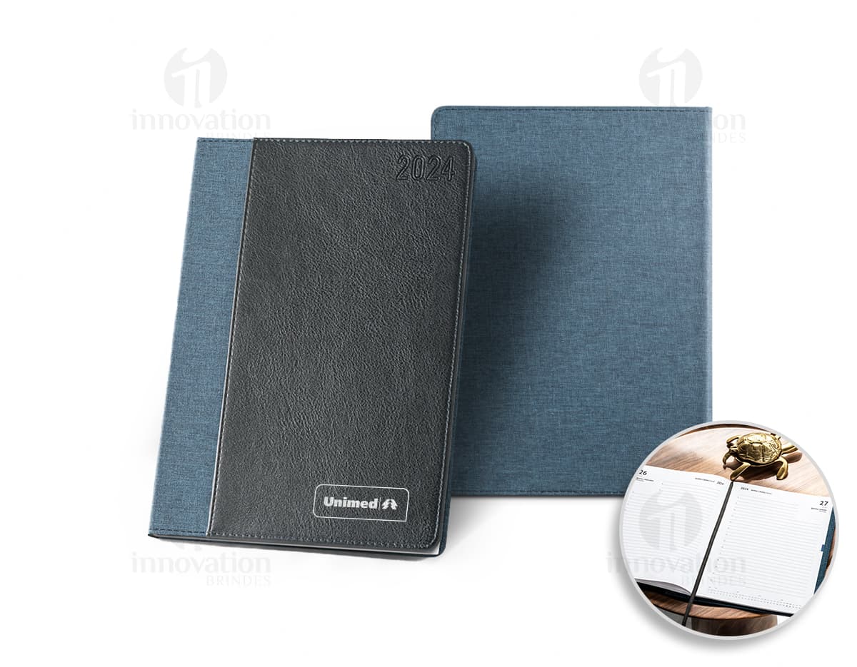 Agenda A5 rPET com bolso frontal para escrita e organização de compromissos, com design moderno e clean. Ideal para uso diário no escritório ou em casa, com espaço para notas e lembretes. Possui capa preta e textura vintage, representando um produto prático e funcional para o dia a dia.