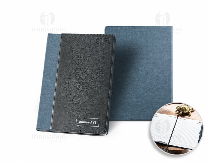 Agenda A5 rPET com bolso frontal para escrita e organização de compromissos, com design moderno e clean. Ideal para uso diário no escritório ou em casa, com espaço para notas e lembretes. Possui capa preta e textura vintage, representando um produto prático e funcional para o dia a dia.