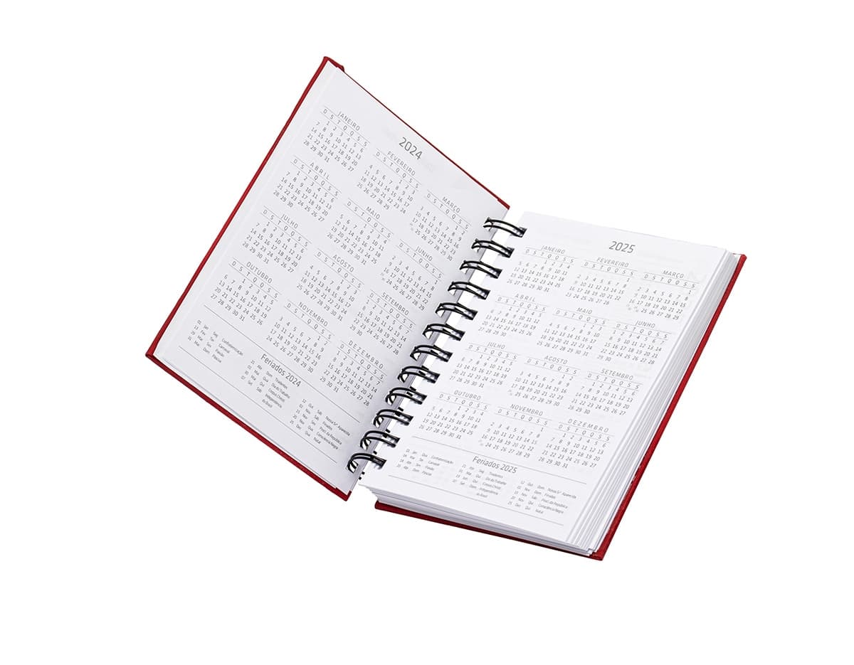 Agenda 2025 Emborrachada em uma mesa de escritório, ao lado de um notebook, dispositivo de internet, roteador, papel em branco, equipamentos de escritório e livros.