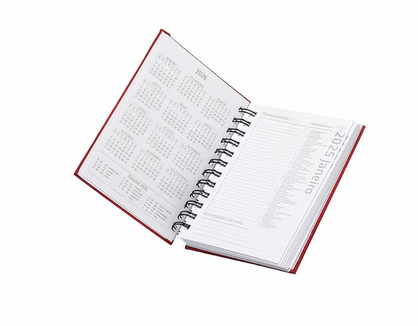 Agenda 2025 Emborrachada em uma mesa de escritório, ao lado de um notebook, dispositivo de internet, roteador, papel em branco, equipamentos de escritório e livros.