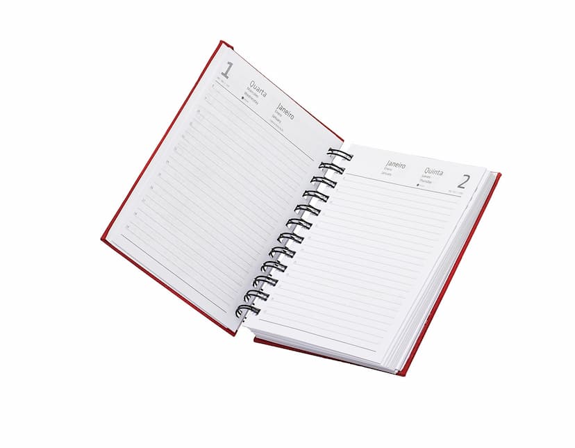 Agenda 2025 Emborrachada em uma mesa de escritório, ao lado de um notebook, dispositivo de internet, roteador, papel em branco, equipamentos de escritório e livros.