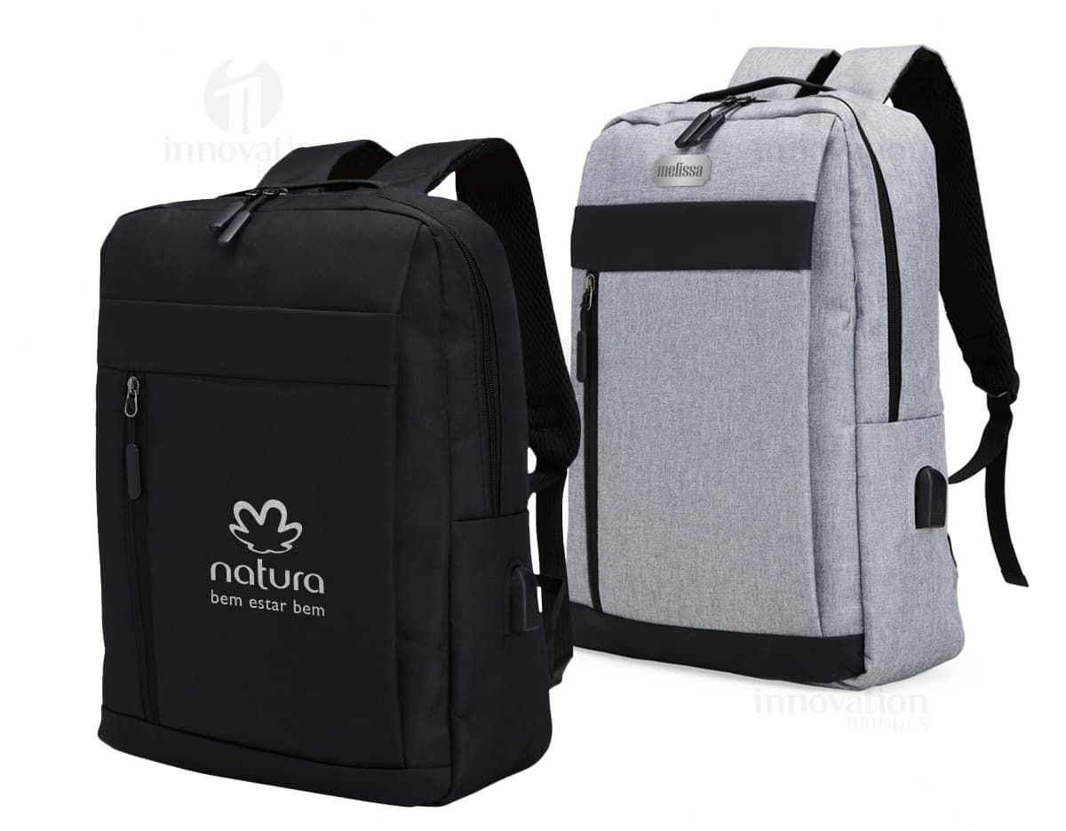 Mochila de nylon preta com capacidade de 21 litros, com detalhes em couro. Possui compartimento para USB, alças, zíper, etiqueta com logotipo e bolso frontal. Ideal para viagens e uso diário, estilo moderno e elegante.