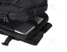 Homem de negócios usando um elegante terno preto, segurando uma mochila de nylon preta de 20 litros com USB. O acessório tem