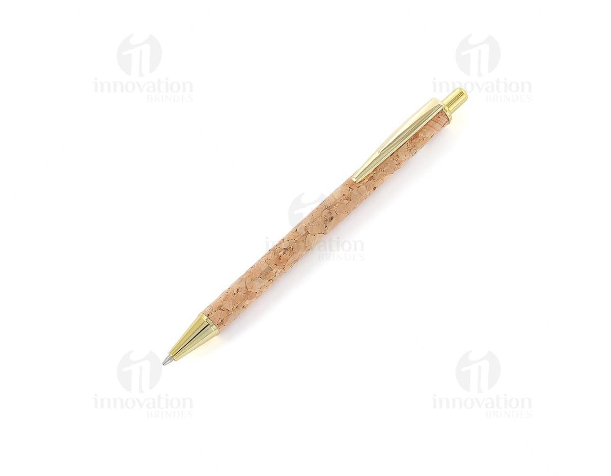 Caneta de metal com detalhes em cortiça sobre um papel, ao lado de um objeto cortante.