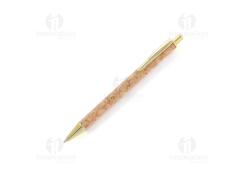 Caneta de metal com detalhes em cortiça sobre um papel, ao lado de um objeto cortante.