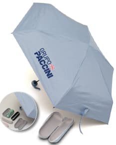 Guarda chuva manual sendo segurado por uma pessoa sorridente em um escritório moderno com um computador e monitor ao fundo. O guarda chuva é preto e está aberto, sugerindo proteção contra a chuva. A pessoa está vestindo roupas profissionais e parece feliz. A imagem transmite a ideia de segurança e conforto em dias chuvosos.