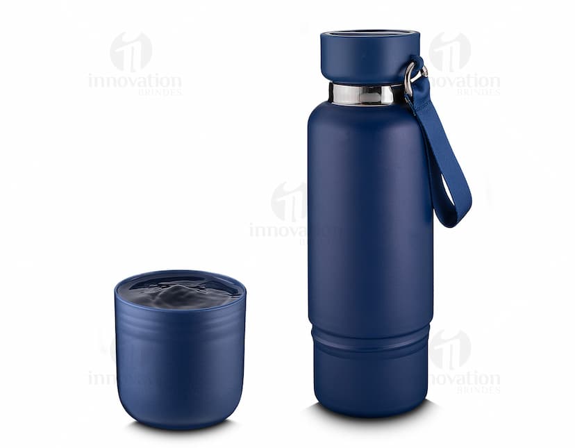 Garrafa térmica inox com mosquetão em ambiente escuro, próximo a um dispositivo eletrônico, fio, lâmpada e alto-falante.