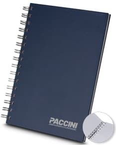Caderno de capa dura preto aberto, com folhas em branco e um lápis sobre ele. Há também um papel e um fichário ao lado. A cena se passa em um ambiente de escritório vazio.