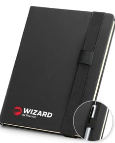 Caderno A5 em couro sintético preto, vazio e aberto em cima de um notebook com teclado preto.