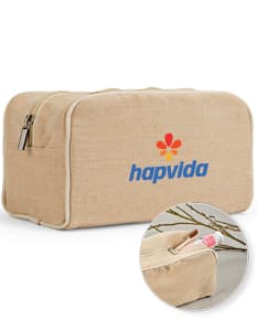 Bolsa de cosméticos marrom e preta, vazia, com fecho de zíper. Ao redor, encontram-se diversos objetos como um carimbo, um dado, uma ferramenta de modelagem, um apontador de lápis, um teclado de computador e uma chave. Há também notas de dinheiro, um cartão de crédito e um saco de compras.