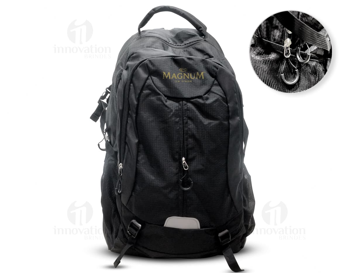 Homem usando mochila de nylon 43 litros em um estúdio. Ele está sorrindo e parece confiante, vestindo um terno preto e uma jaqueta de couro.