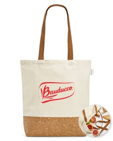 Sacola de compras feita de 70% algodão reciclado, com textura marrom de juta, vazia e sem ninguém perto. Na sacola há pão, embalado em papel, com uma etiqueta em branco presa ao cabo. A sacola está em uma loja de alimentos, decorada com uma fita amarela e um cartão de presente.