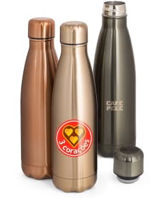 Garrafa em aço inox, com rótulo, contendo líquido alcoólico. A garrafa está em um ambiente de celebração, em um bar ou restaurante, rodeada por outras garrafas e copos. A imagem mostra a transparência e a limpeza do recipiente, destacando o luxo e a qualidade do produto.