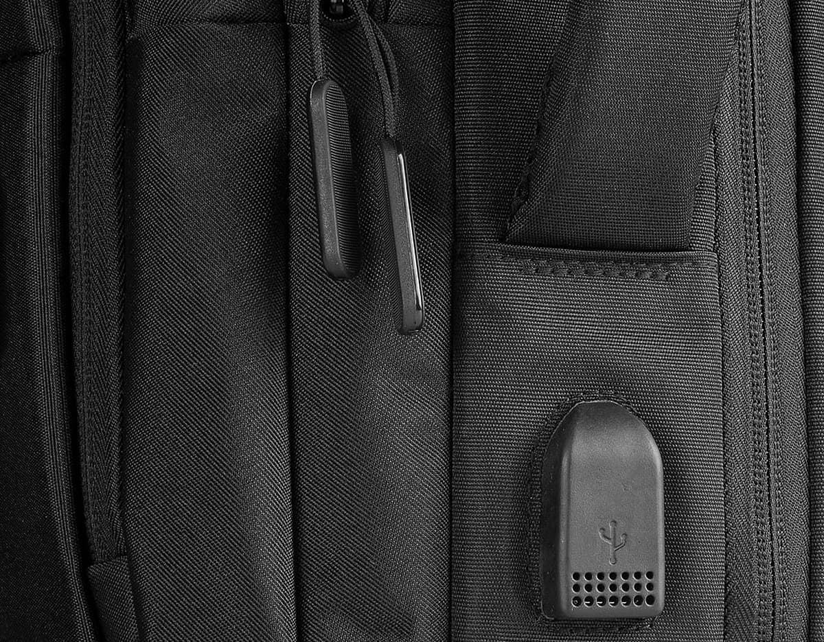 Mochila pasta para notebook em couro preto, com zíper, botões, bolso para laptop e detalhes em metal. Modelo corporativo e moderno, ideal para homens de negócios.